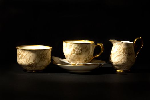 An elegant tea cup with a saucer, milk jug, suger bowl, a spoon and tea bag