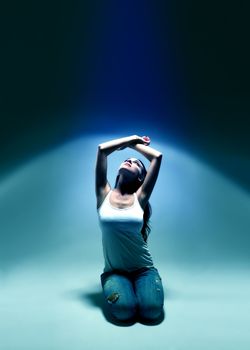 young woman looking upwards into blue spotlight atmosphere