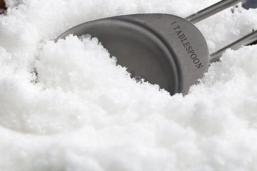 Close-up of teaspoon in sugar granules.