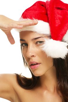 young woman wearing santas hat shields her sight on white background