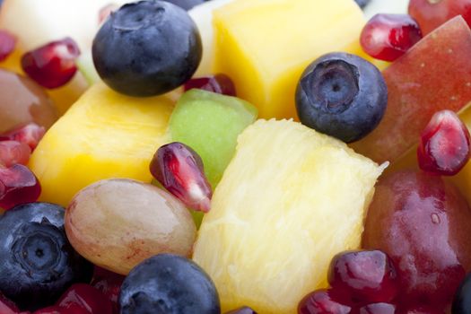 Close-up of fruit salad with blueberries, pomegranate seeds, pineapple and apple slices.