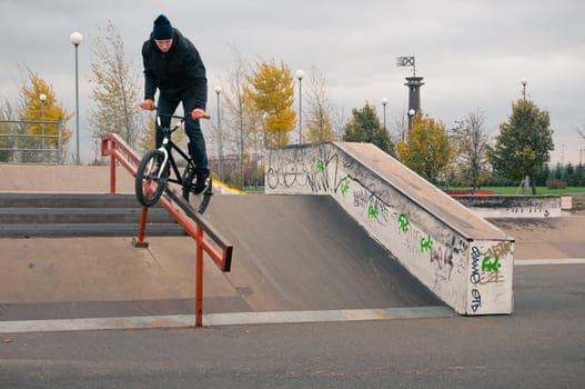 Biker doing crank slide grind trick down to red rail