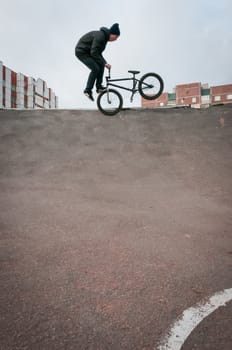 Biker doing footjam tailwhip trick with houses on background