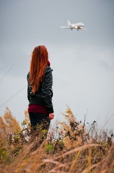 Pretty girl with red hair looking on small plane