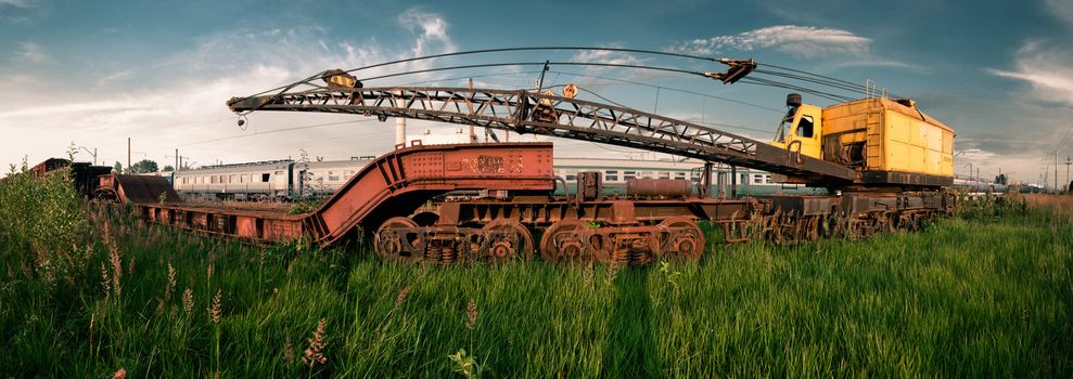 Old colored and rusted railway crane on rails