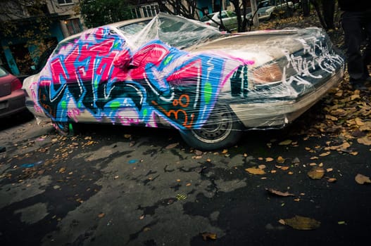 Graffiti style painted broken car in city