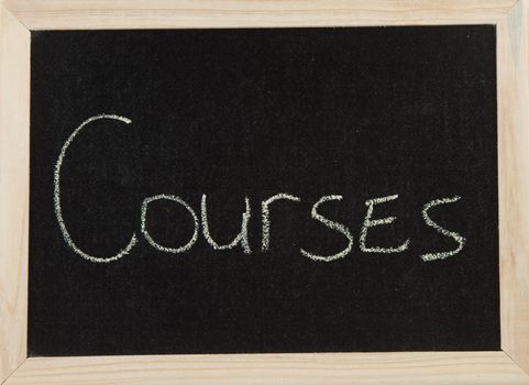 A black board with a wooden frame and the word 'COURSES' written in chalk.