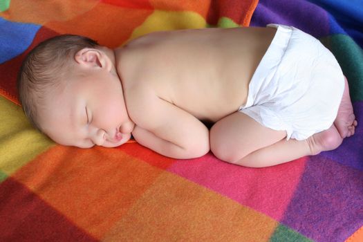 Newborn baby boy lying on a colorful blanket