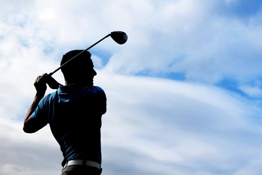 Young golfer driving with a wood against cloudy skies