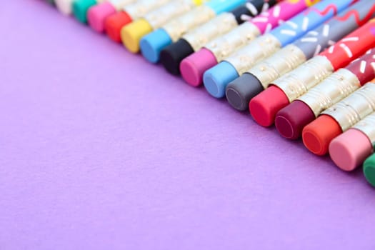 Backend erasers of color pencils in a row on purple