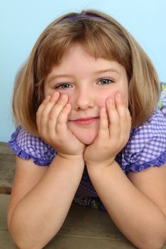 Cute little girl wearing a purple dress against blue background