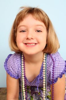 Cute little girl wearing a purple dress against blue background