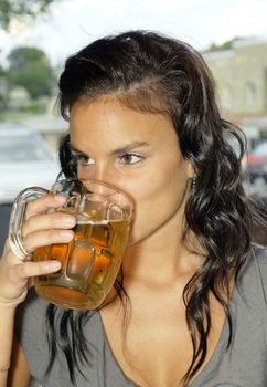 Beautiful young woman drinking beer in big glass buck, can be binging, alcoholism or other addiction.