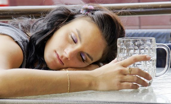 Young woman asleep outdoors on pub's terrace after drinking too much beer.