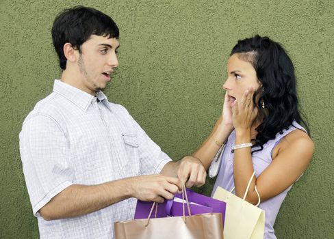 Consumerism concept: caught in th act, couple arguing about the young woman's many expensive purchases during her last shopping spree.