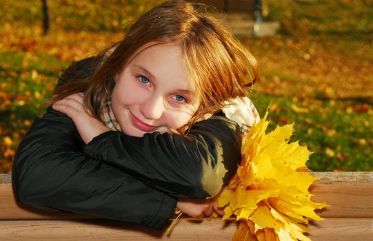 Portrait of a beautiful teenage girl with yellow fall maple leaves