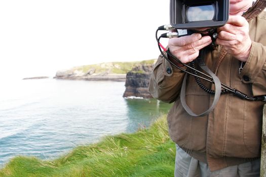 a cameraman filming on the cliff edge in ballybunion ireland