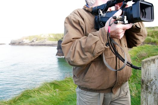 a cameraman filming on the cliff edge in ballybunion ireland