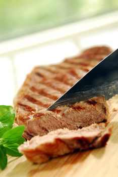 Grilled steak being cut on a cutting board