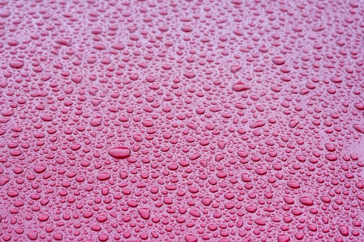 a picture of water drops on a red metal surface