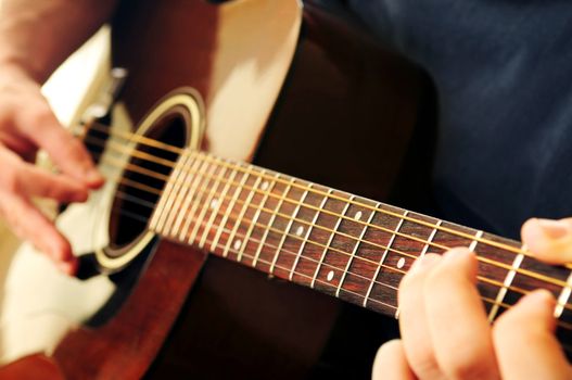 Hands of a person playing an acoustic guitar