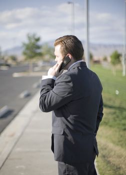 Businessman talking on his cell phone about business while standing outside in his business suit