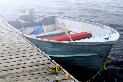 Empty old boat at a dock on a misty lake