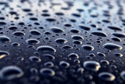 Abstract background of water drops on a blue metal surface