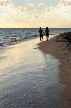 Couple taking a walk on a sandy beach of tropical resort