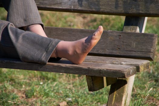 Foot of the girl laying on a wooden bench