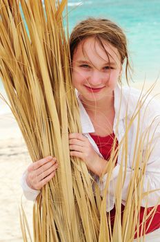 Portrait of a young girl on tropical beach with palm tree branch
