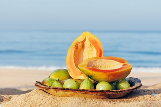 Exotic tropical fruit on the leaves plate on the sandy beach