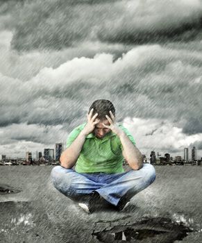 Young man who sits on asphalt and thinking