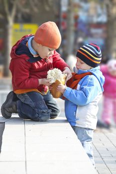 The brothers share the bread for a walk in autumn park