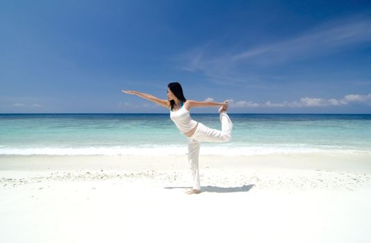 Woman practising Yoga (Warrior Position) on the beach.