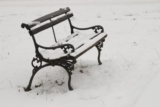 Old bench in park covered with snow