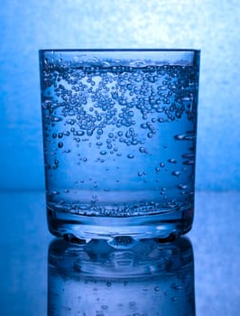 Glass of water with bubbles, in blue