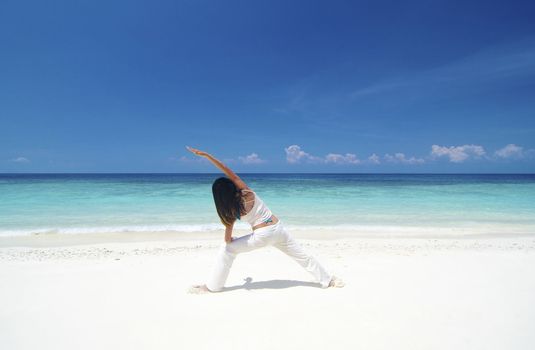 Woman practicing Yoga (Warrior Position) on the beach.