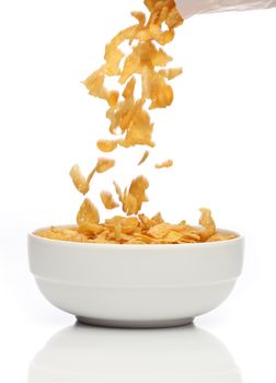 Pouring cornflakes into a bowl, over white background