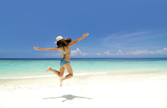 Bikini young girl is jumping up in the air at the beach