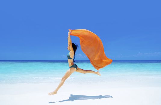 Pretty young bikini girl is jumping up in the air at the beach