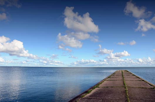 Concrete pier or bridge in sea. Calm sea water and sky view.