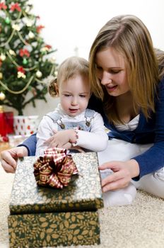 little girl and her mother unpacks the gift at Christmas