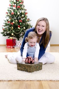 little girl and her mother unpacks the gift at Christmas