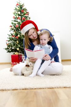 Girl and her mom reading book at Christmas