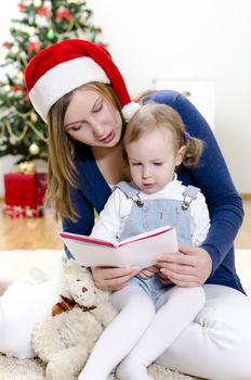Girl and her mom reading book at Christmas