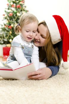 Girl and her mom reading book at Christmas