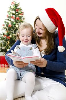 Girl and her mom reading book at Christmas