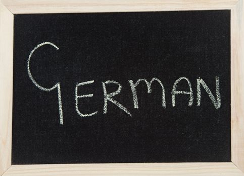 A black board with a wooden frame and the word 'GERMAN' written in chalk.