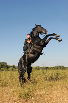 young man and her beautiful black stallion rearing up